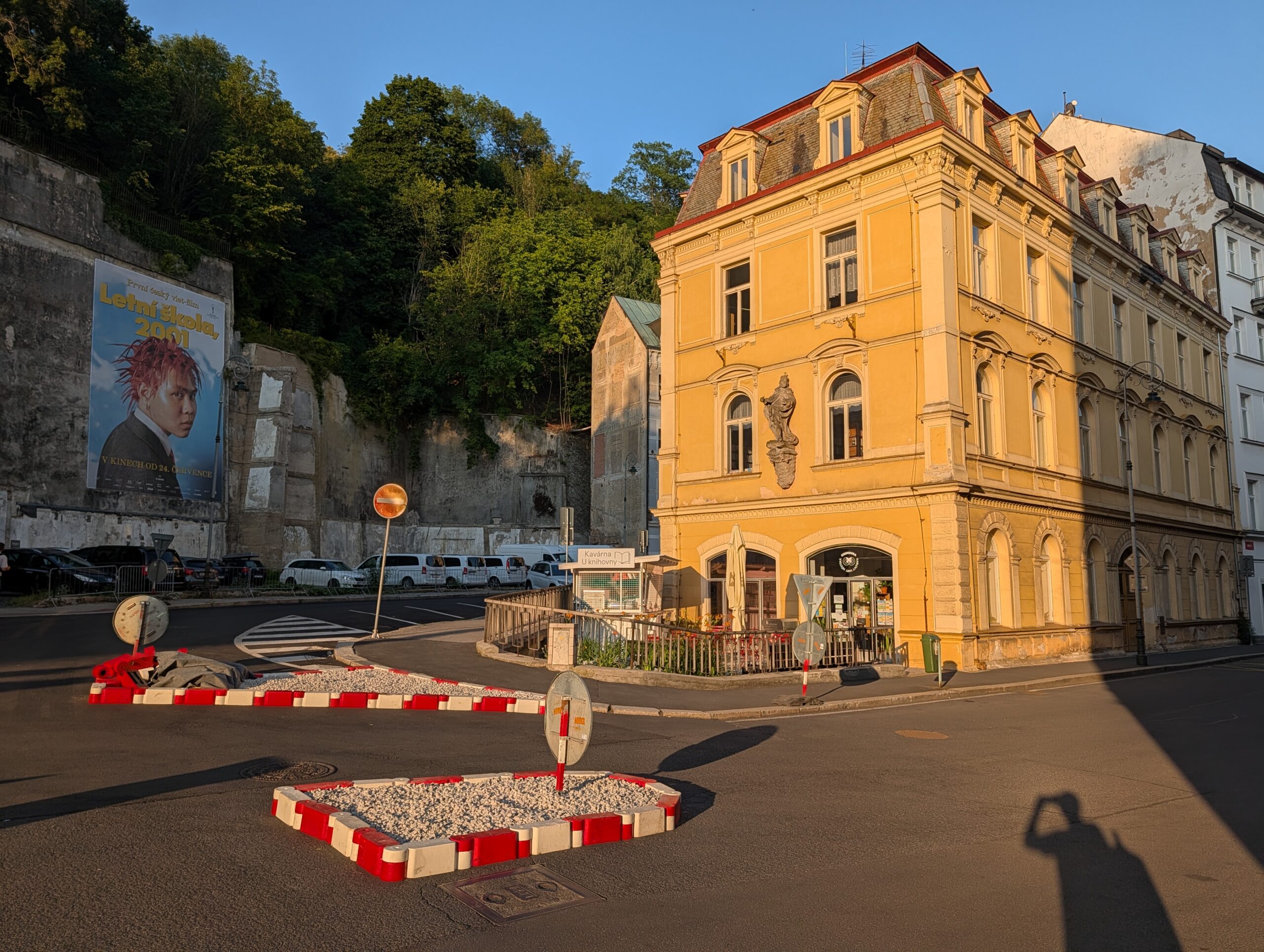 Gelbes Gebäude der Stadtbibliothek in Karlsbad vor einem bewaldeten Hang