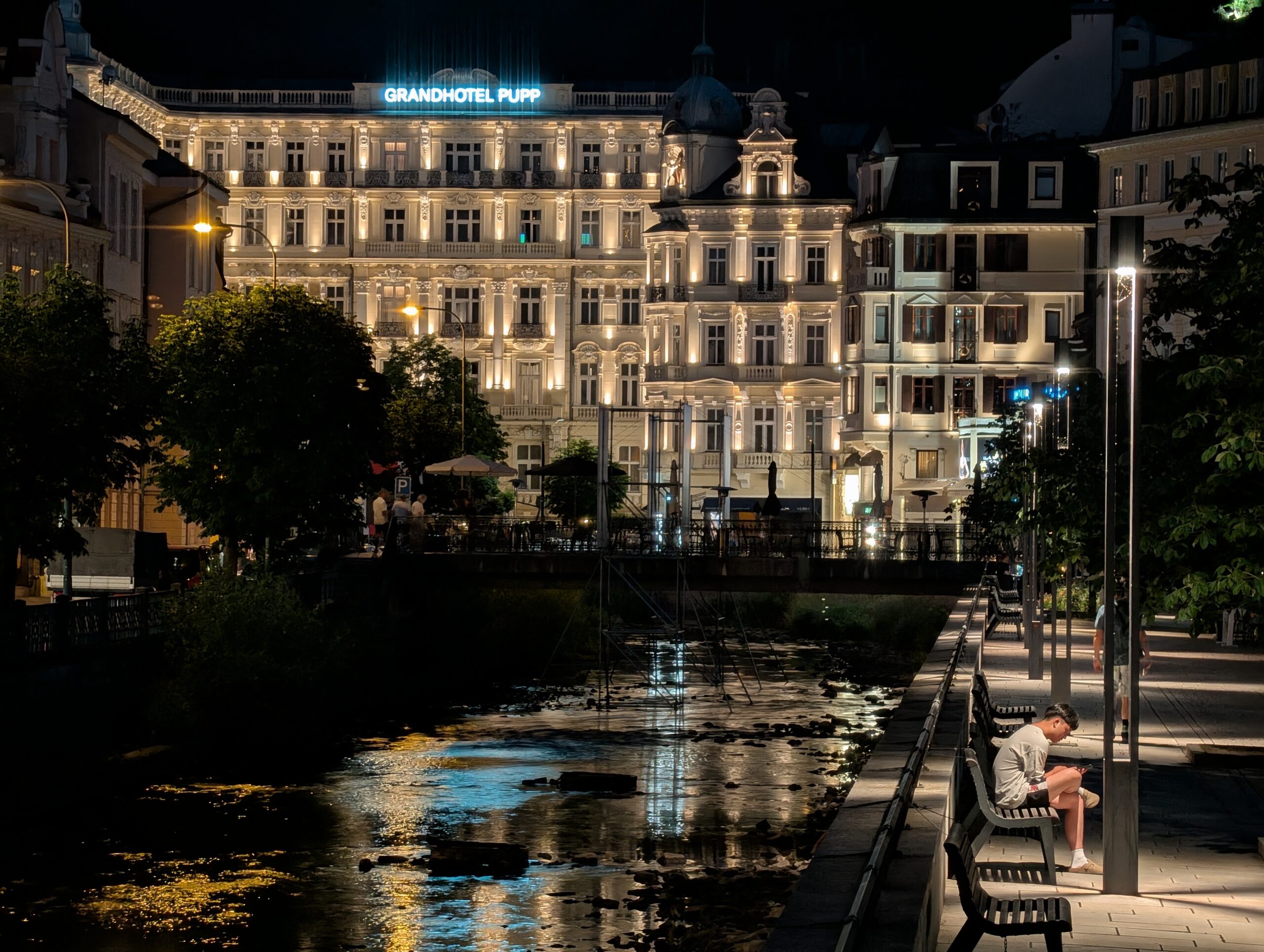 Beleuchtetes Grandhotel Pupp hinter der Teplá-Promenade in Karlsbad bei Nacht