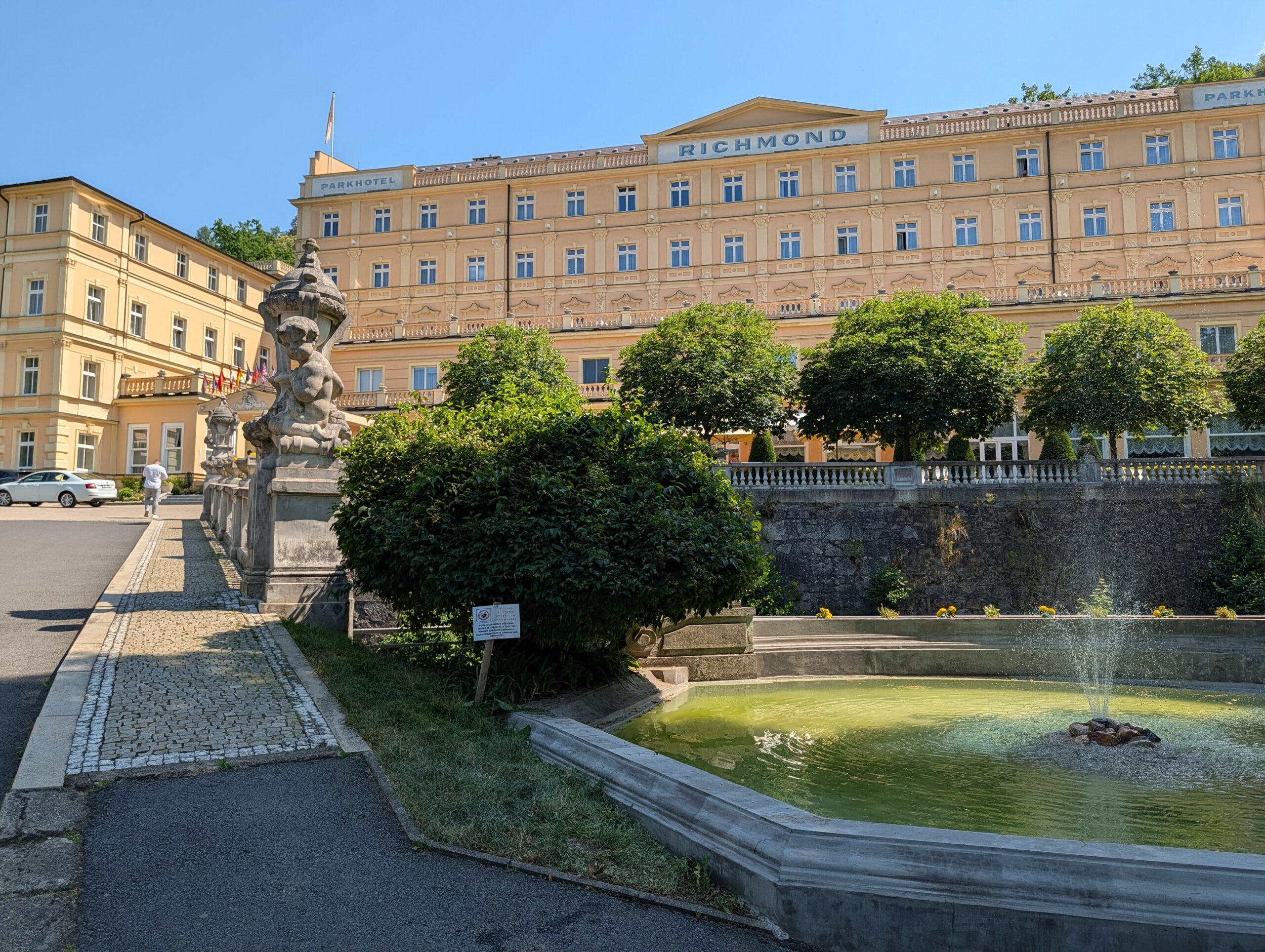 Parkhotel Richmond in Karlsbad mit historischer Fassade, Springbrunnen und Skulpturen in der Parkanlage.