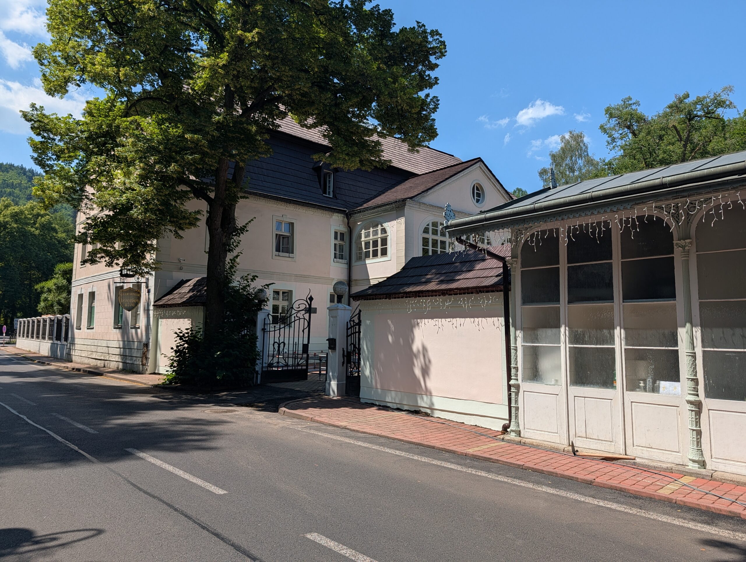 Historischer Posthof (Poštovní dvůr) mit heller Fassade, Eingangstor und verzierter Veranda in Karlsbad.