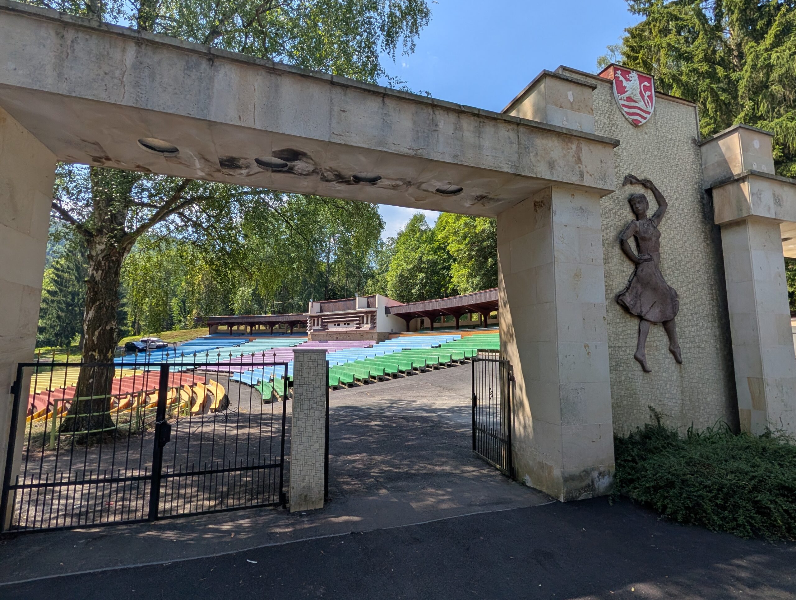 Eingangsportal des Amphitheaters und Sommerkinos Karlsbad mit farbigen Sitzreihen im Freien.