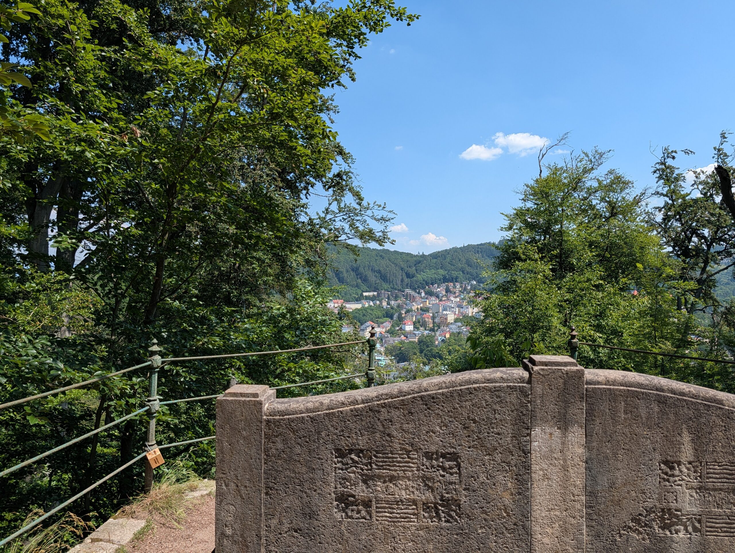 Wolfsruhe-Bank (Wolfova lavička) aus Stein mit Ausblick auf Karlsbad und die bewaldeten Hügel.