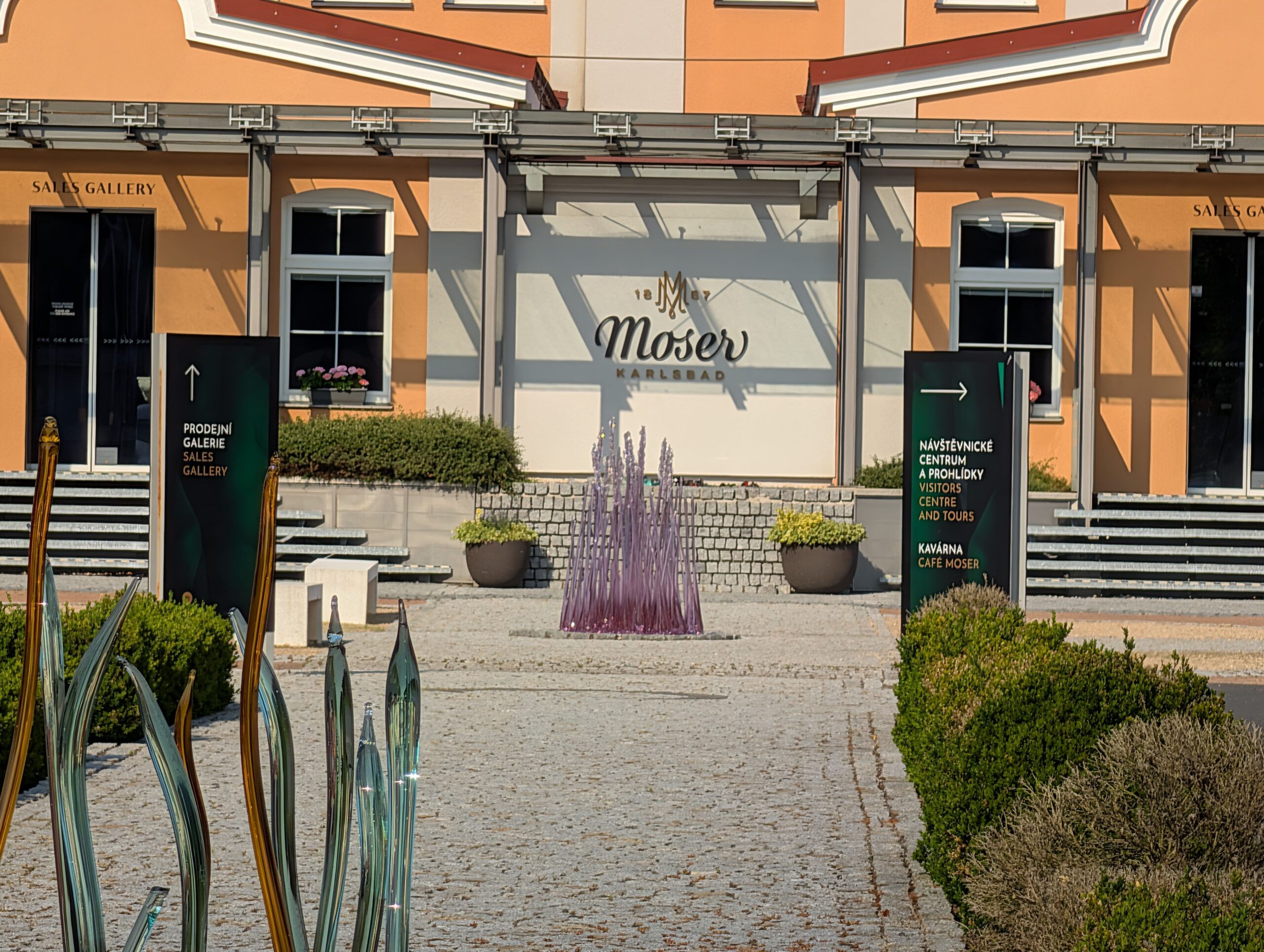 Eingangsbereich des Moser Besucherzentrums und Glasmuseums (Návštěvnické centrum Moser) mit Glasinstallation und Moser-Logo in Karlsbad.