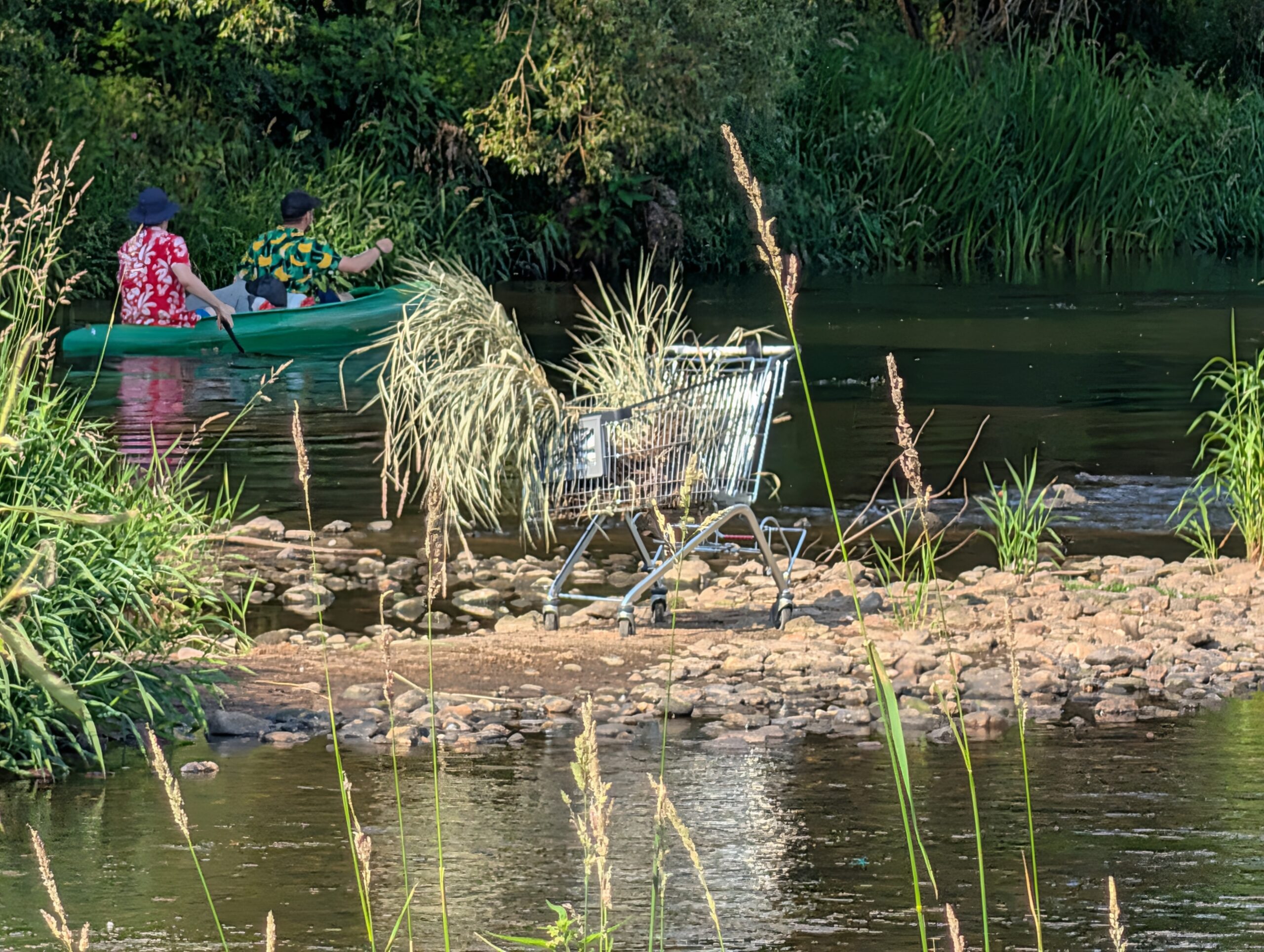 Kanufahrer auf der Eger an der Enteninsel (Kachní ostrov) mit einem Einkaufswagen im flachen Flussufer in Karlsbad.