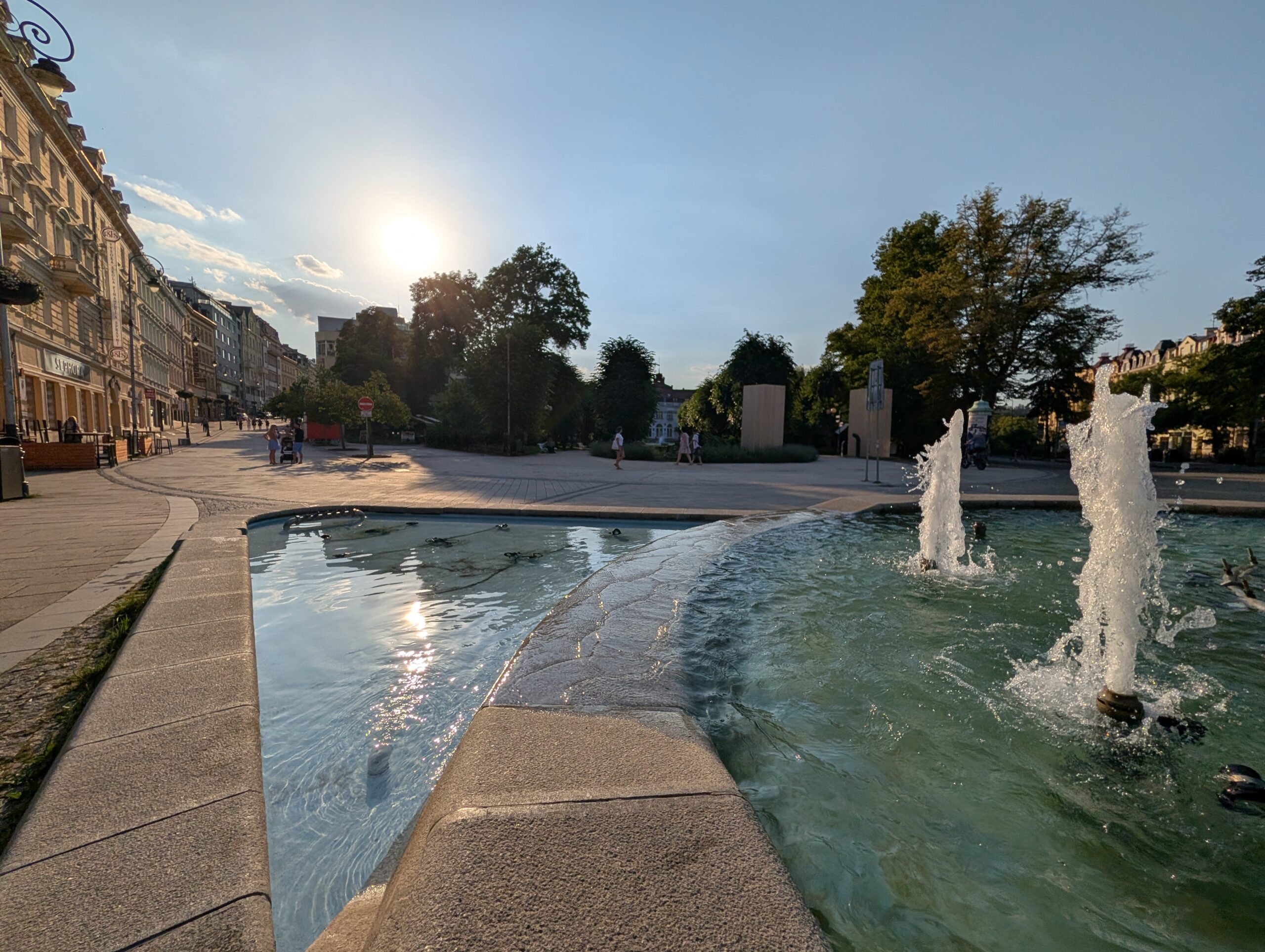 Brunnen mit Glasobelisk am T.-G.-Masaryk-Platz (náměstí T. G. Masaryka) vor historischen Gebäuden in Karlsbad.