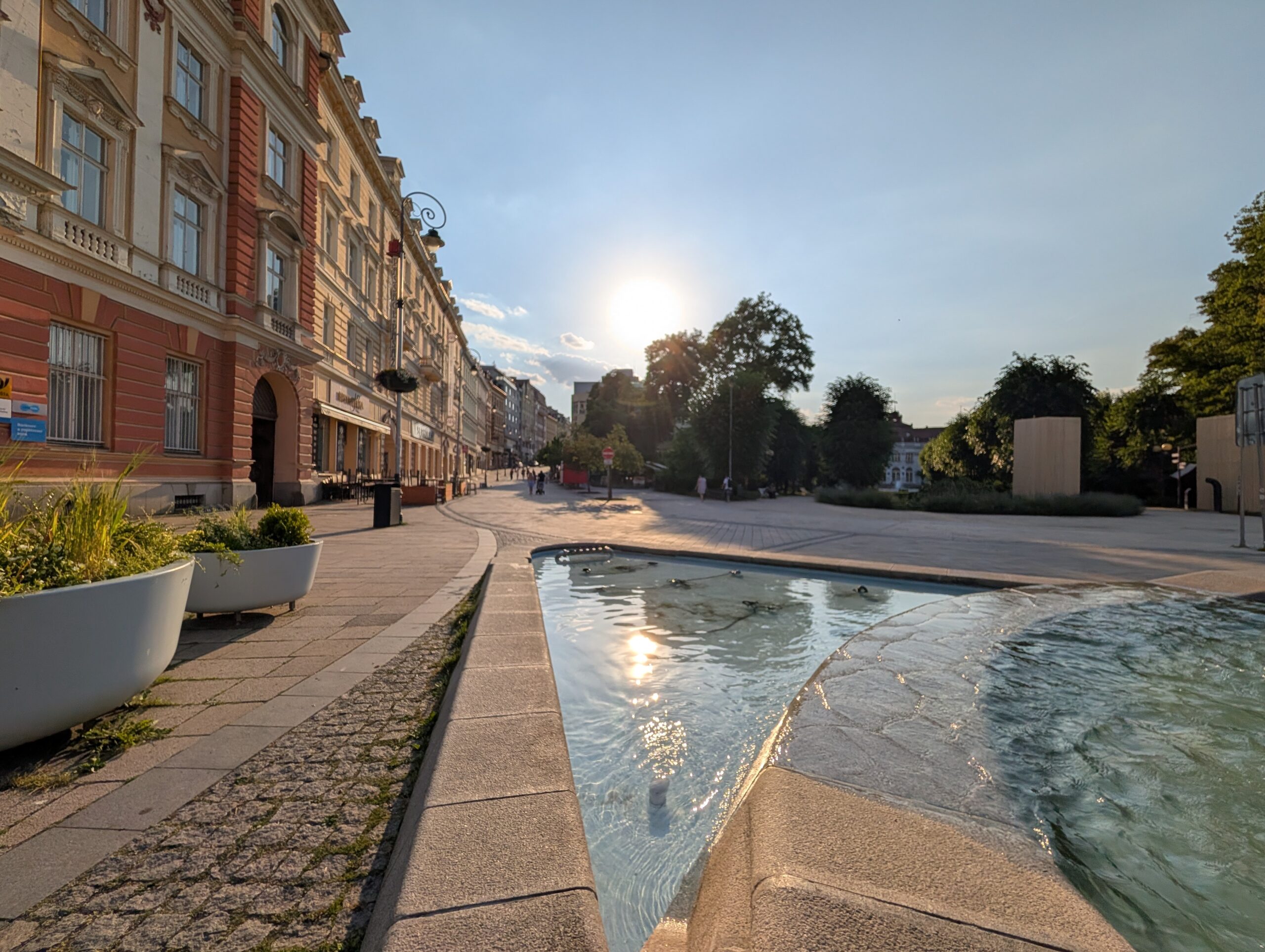 Brunnen mit Glasobelisk am T.-G.-Masaryk-Platz (náměstí T. G. Masaryka) vor historischen Gebäuden in Karlsbad.