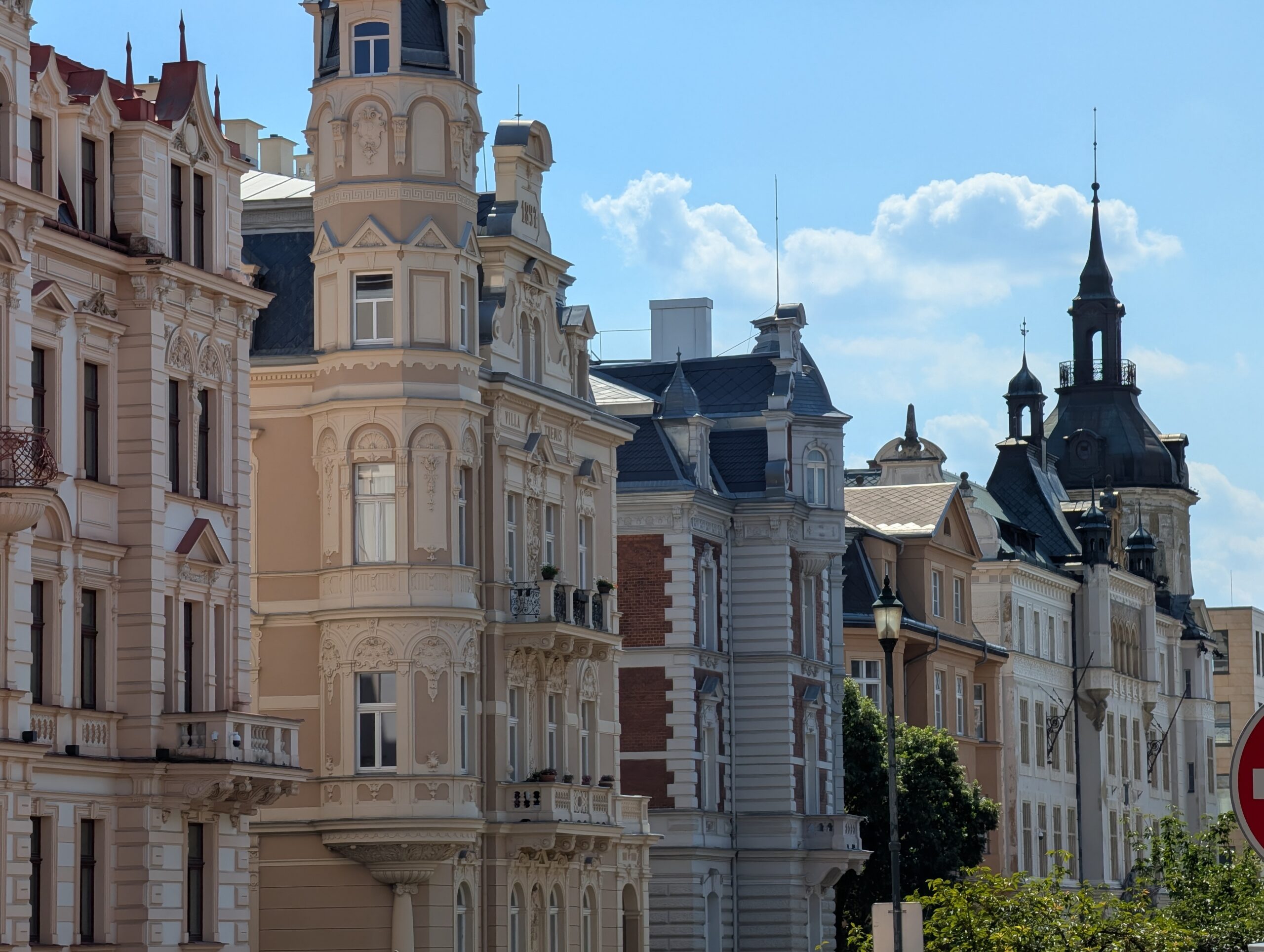 Historische Gebäude mit verzierten Fassaden, Erkern und Türmen entlang einer Straße.