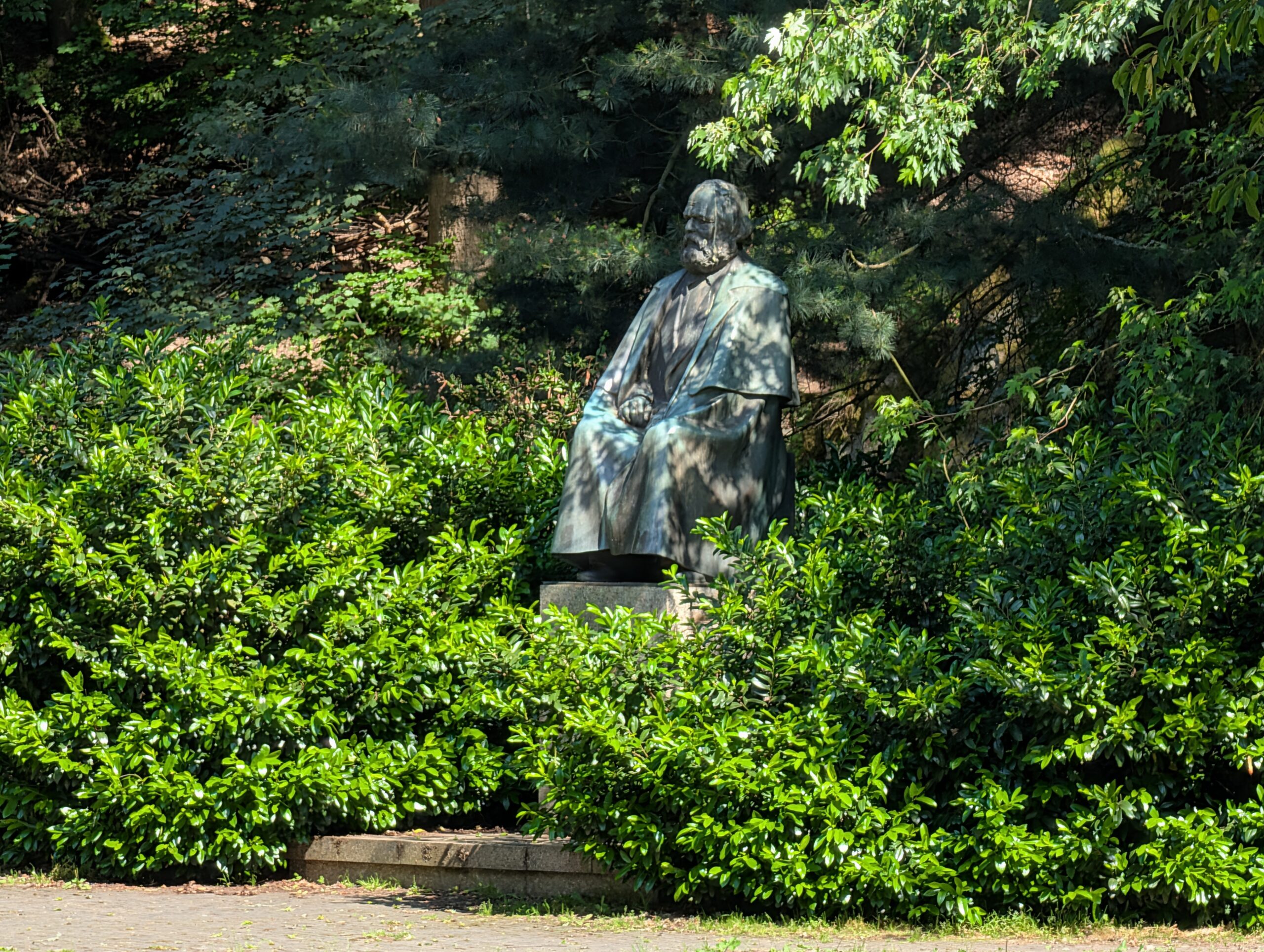 Karl-Marx-Statue in einer Grünanlage mit Bäumen und Sträuchern in Karlsbad.